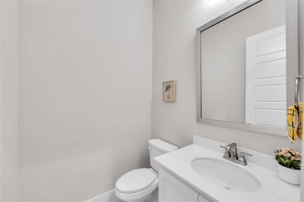 2971 Gaulding Drive, Prosper, TX 75078 Vanity with a white countertop, undermount sink, chrome faucet, wall-mounted mirror, and a two-piece toilet