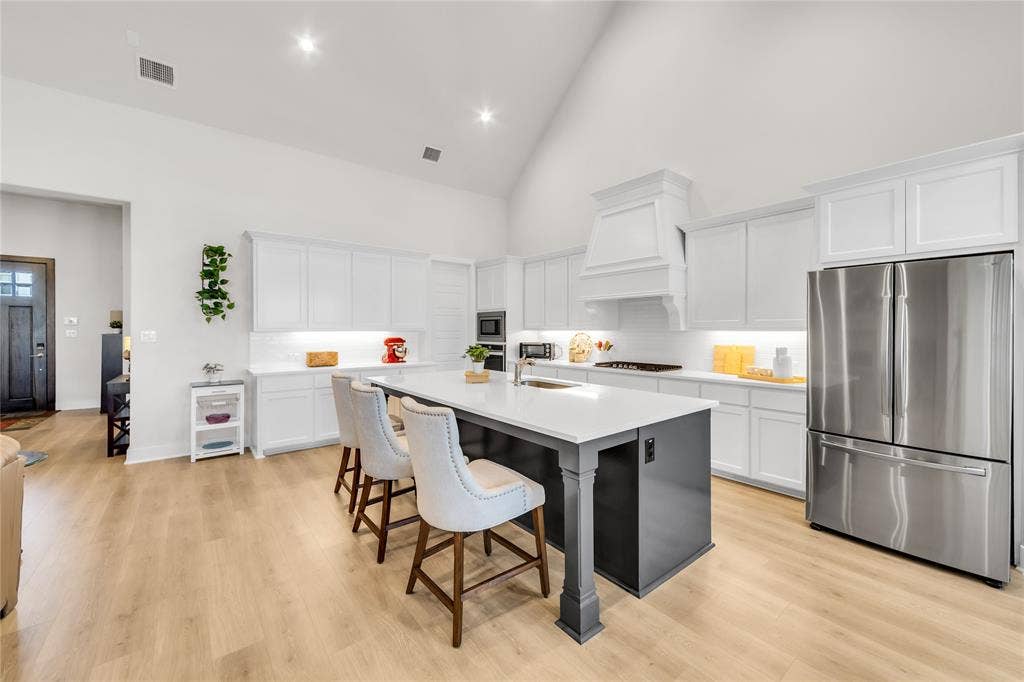 2971 Gaulding Drive, Prosper, TX 75078 Kitchen featuring a vaulted ceiling, central island with a contrasting base, white cabinetry, light-toned wood-finish flooring, and recessed lighting