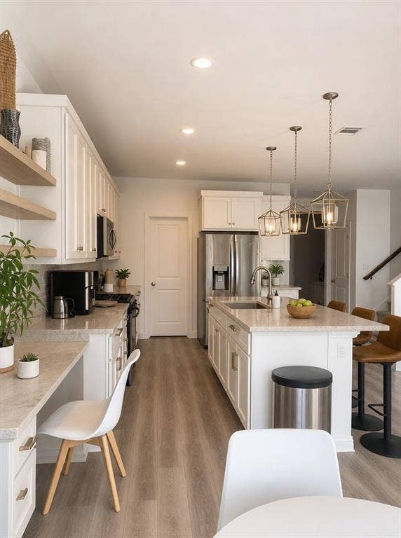1816 Purtis Creek Drive, Forney, TX 75126 Kitchen featuring white cabinetry, wood-finish flooring, stone-composite countertops, a central island with an undermount sink, and three geometric pendant lights