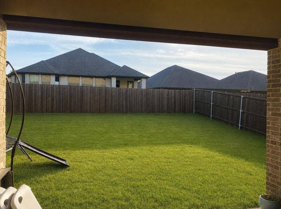 1816 Purtis Creek Drive, Forney, TX 75126 Backyard featuring a manicured lawn, wood-slat perimeter fencing, and a covered brick-columned patio