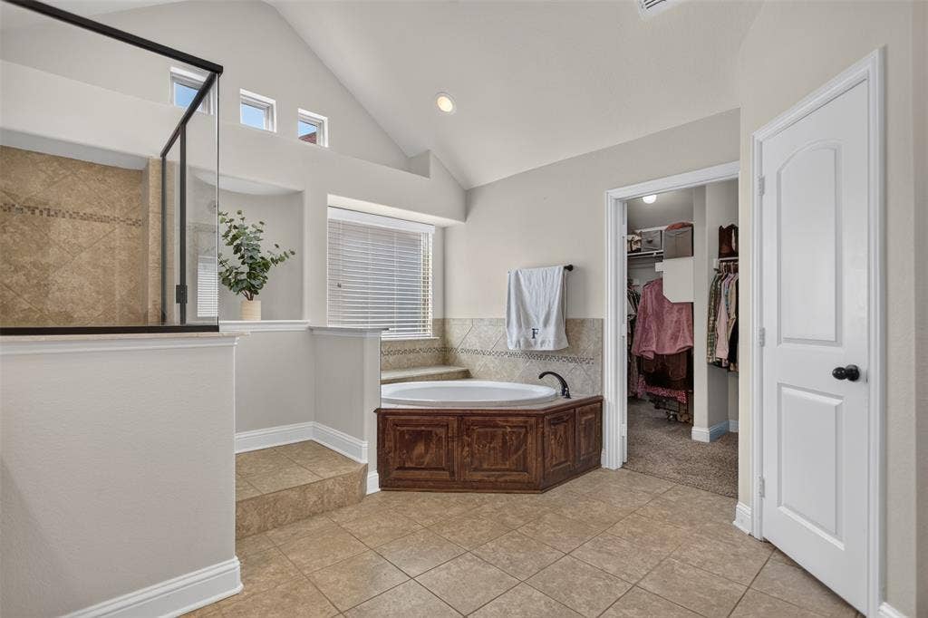 122 Anns Way, Forney, TX 75126 Vaulted ceilings, corner soaking tub with wood-finish cabinetry, ceramic tile flooring, glass-enclosed shower with tile surround, and built-in recessed wall niche