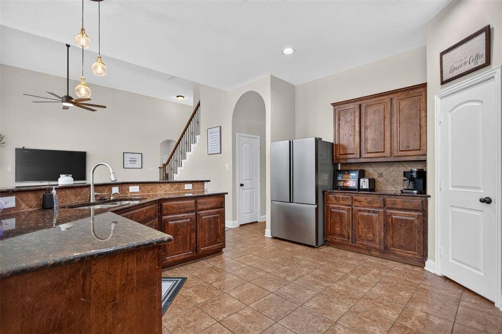 122 Anns Way, Forney, TX 75126 Kitchen featuring dark wood cabinetry, stone-finish countertops, tile flooring, tile backsplash, and multi-light pendant fixtures