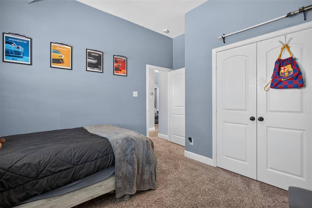 122 Anns Way, Forney, TX 75126 Neutral wall-toned room featuring plush carpeting, dual-panel closet doors with matte black hardware, and an exposed overhead sliding track system