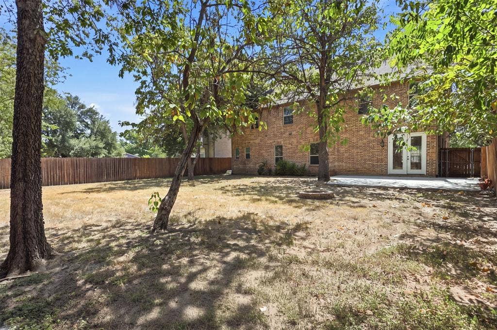 336 Kaye Street, Coppell, TX 75019 Brick exterior featuring a concrete patio, wood privacy fencing, and mature trees