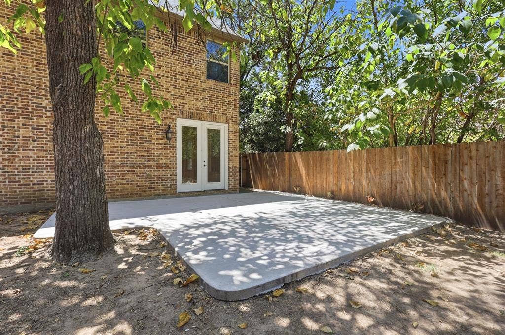 336 Kaye Street, Coppell, TX 75019 Exterior brick facade featuring a concrete patio, double glass-panel doors, and a wood privacy fence