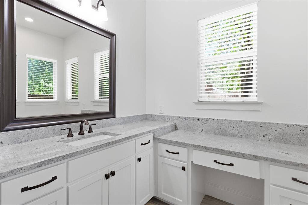 336 Kaye Street, Coppell, TX 75019 Bathroom vanity featuring white shaker-style cabinetry, light-toned stone countertops, a rectangular undermount sink with a widespread faucet, a large framed mirror, and matte black hardware