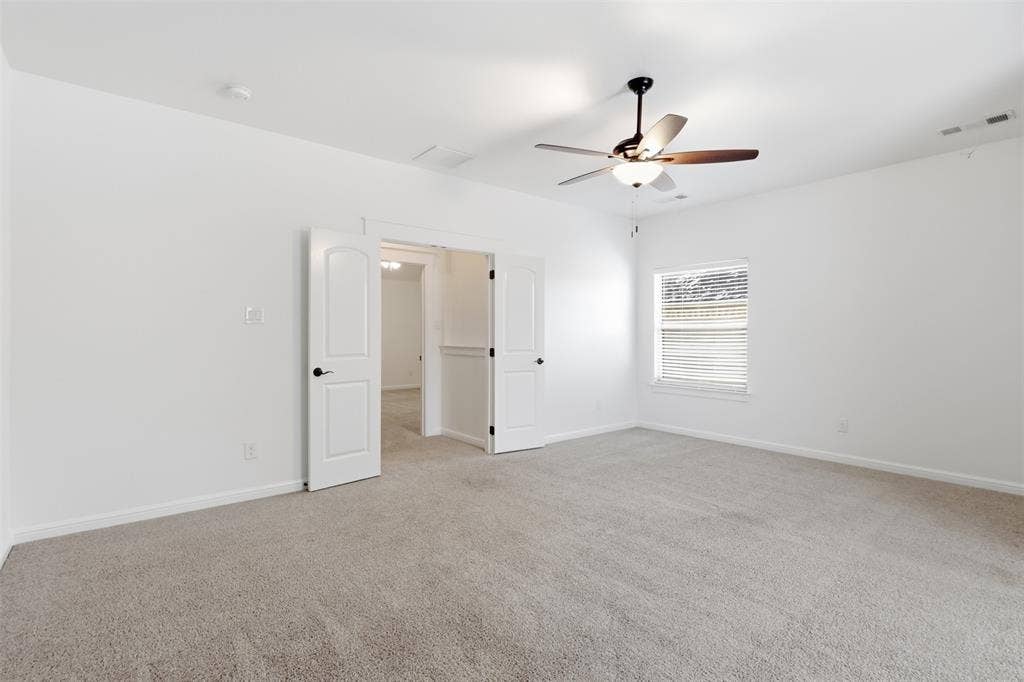 336 Kaye Street, Coppell, TX 75019 Neutral-toned carpeted flooring, white interior walls, ceiling fan with integrated lighting, and white double doors featuring matte black hardware