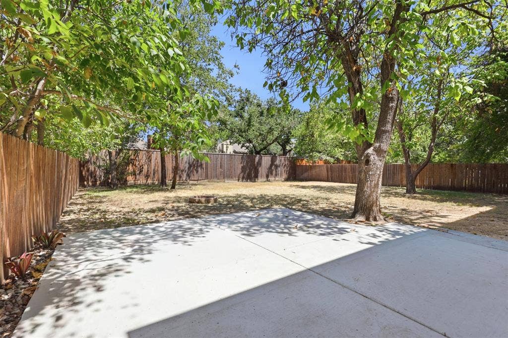 336 Kaye Street, Coppell, TX 75019 Backyard featuring a concrete patio, wood privacy fencing, and mature trees