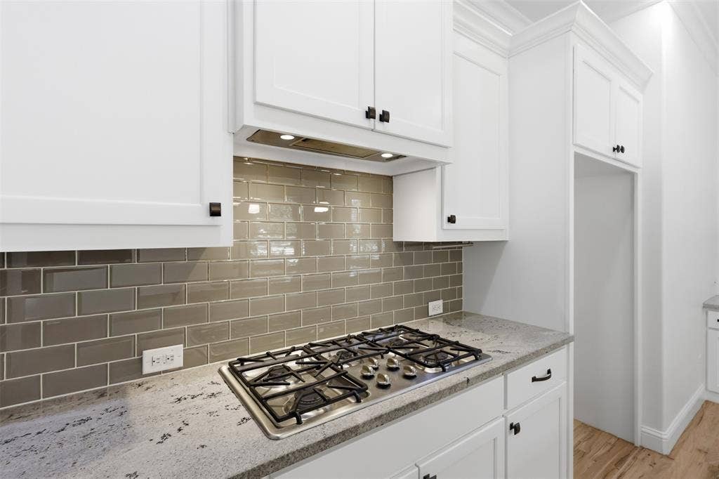 336 Kaye Street, Coppell, TX 75019 Kitchen featuring white Shaker-style cabinetry, neutral subway tile backsplash, stone countertops, and a built-in stainless steel gas cooktop