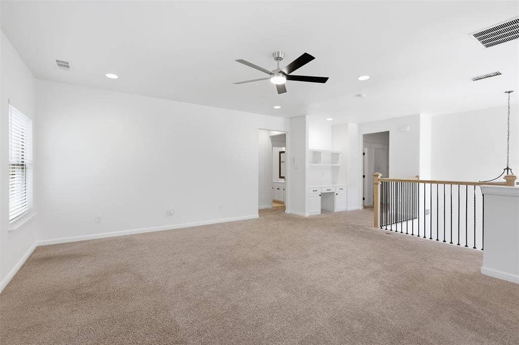 336 Kaye Street, Coppell, TX 75019 Open living space featuring recessed lighting, a ceiling fan with integrated light, carpeted flooring, a built-in desk with overhead cabinetry, and an open metal spindle railing