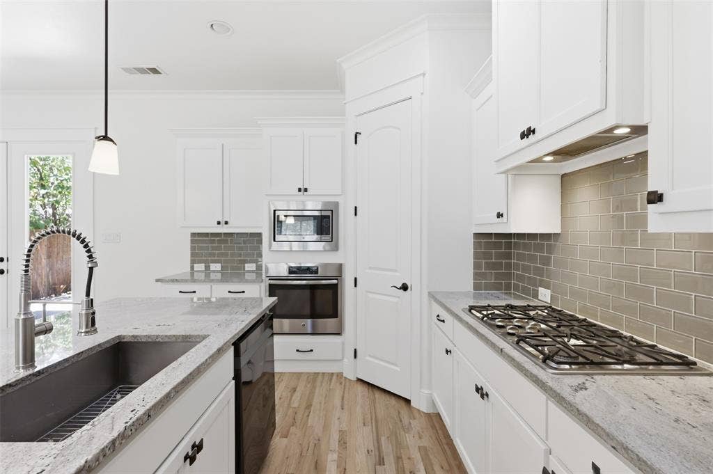 336 Kaye Street, Coppell, TX 75019 Kitchen featuring shaker-style cabinetry, light-toned stone countertops, a subway tile backsplash, stainless steel built-in appliances, and wood-finish flooring
