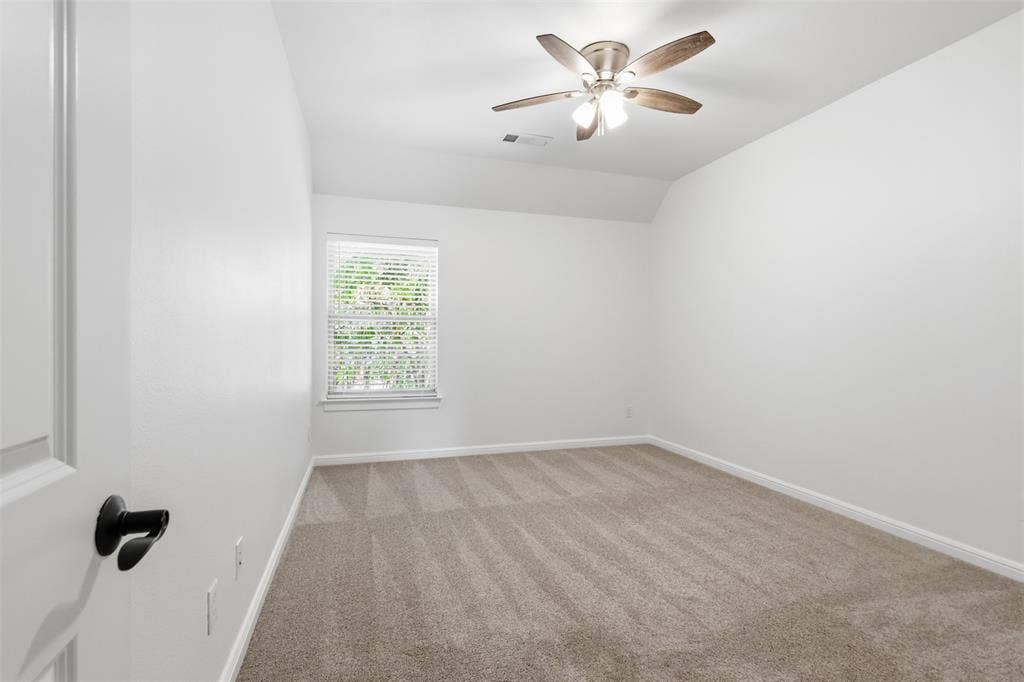 336 Kaye Street, Coppell, TX 75019 Neutral-toned carpeting, vaulted ceiling, multi-blade ceiling fan with integrated lighting, and a single window with horizontal blinds