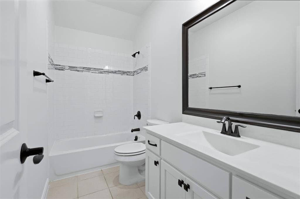 336 Kaye Street, Coppell, TX 75019 White vanity with integrated countertop and sink, matte black hardware, framed wall mirror, and tub-shower combination featuring decorative mosaic tile inlay