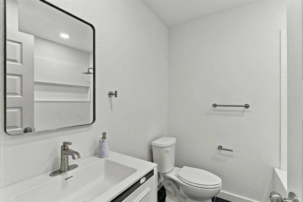 Bathroom featuring a vanity with an integrated sink, brushed metal faucet, rectangular mirror with a black frame, and wall-mounted hardware