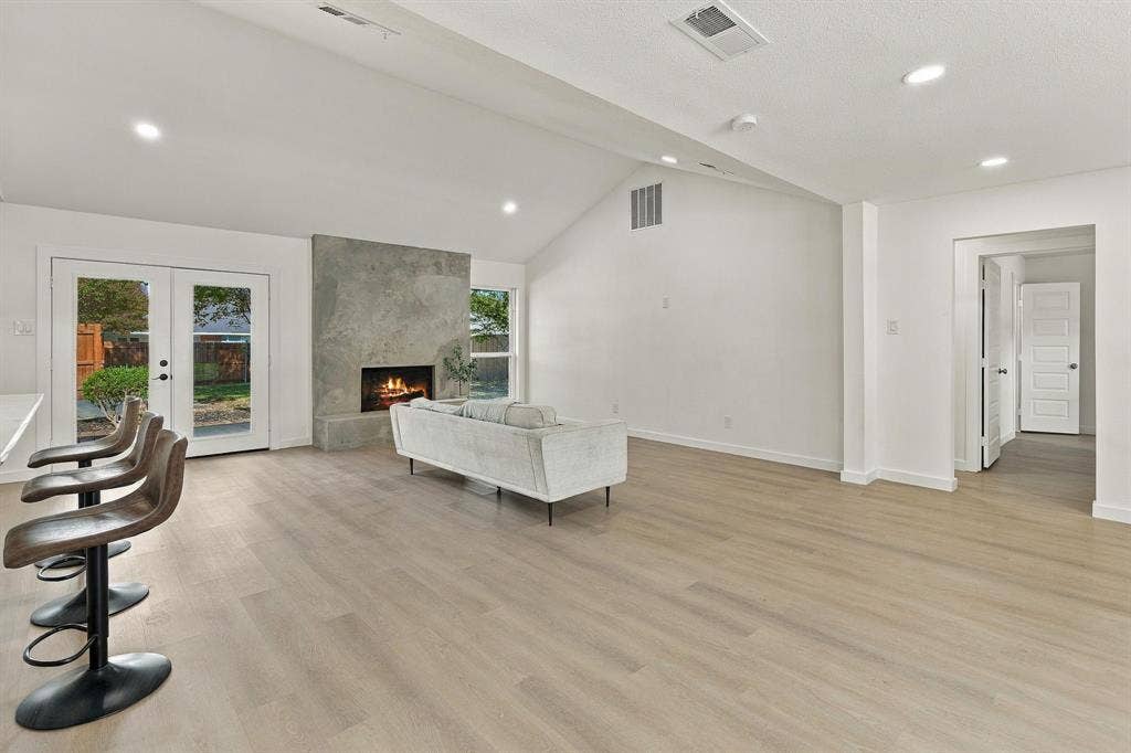 Vaulted ceilings, wood-finish flooring, floor-to-ceiling stone fireplace, and double French doors