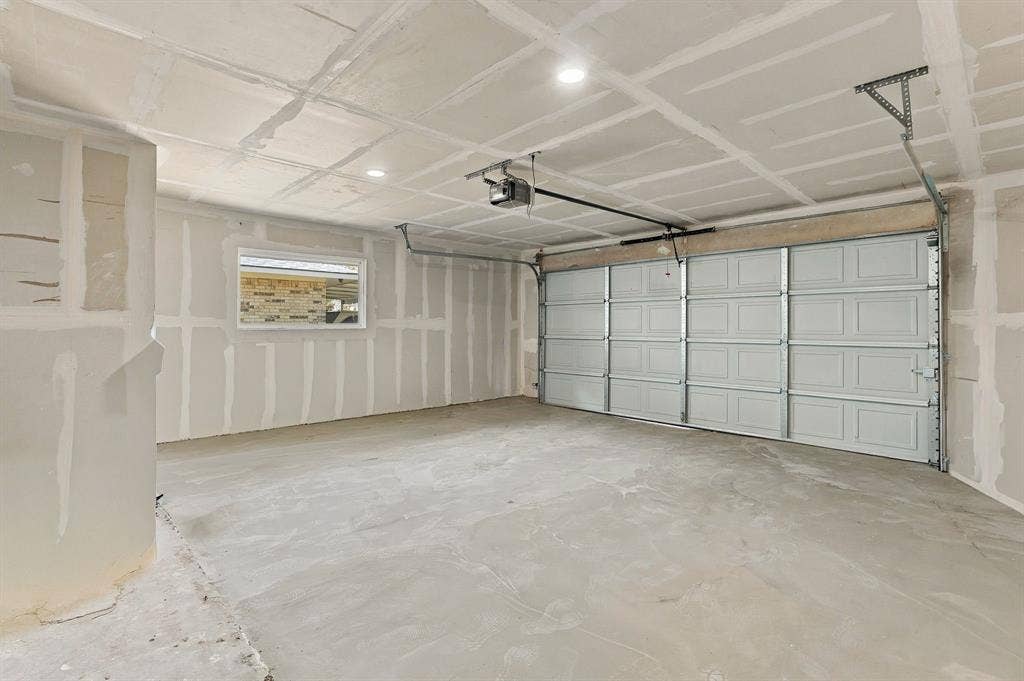 Multi-car garage featuring a sectional door, concrete flooring, recessed lighting, and a single window