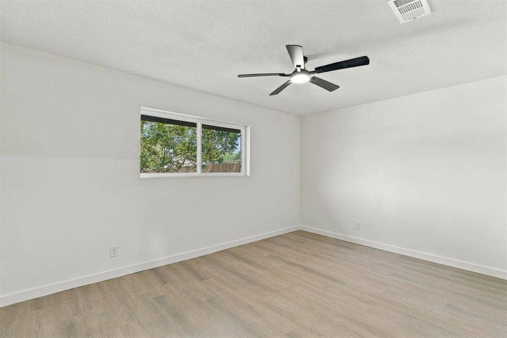 Neutral interior featuring wood-finish flooring, a contemporary ceiling fan with integrated lighting, and a single-pane horizontal window