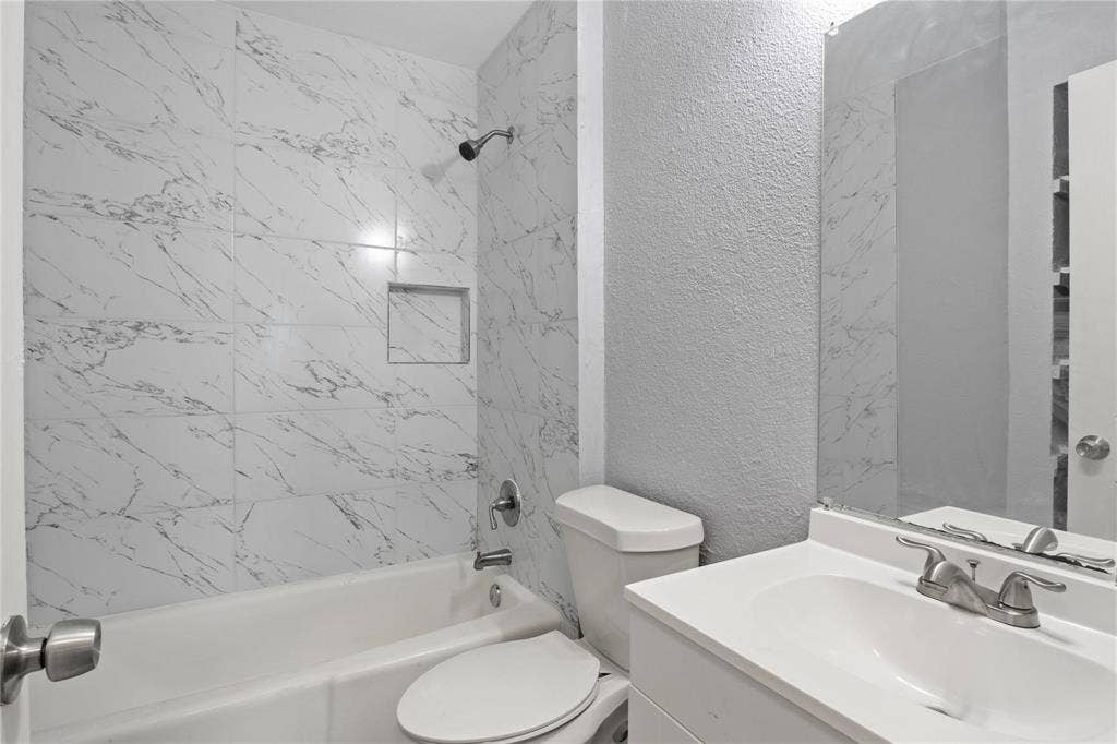 6543 Gentle River, Dallas, TX 75241 Full-height shower surround with veined tile finish and built-in recessed niche, chrome shower hardware, vanity cabinet with integrated sink basin, chrome dual-handle faucet, and frameless wall-mounted mirror