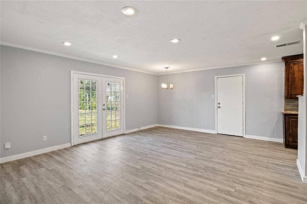 6543 Gentle River, Dallas, TX 75241 Neutral-toned interior space featuring wood-finish flooring, recessed lighting, double French doors, and a multi-light chandelier