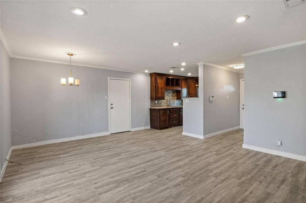 6543 Gentle River, Dallas, TX 75241 Living area featuring wood-finish flooring, recessed lighting, and a multi-light chandelier, with a partial wall revealing kitchen cabinetry and a tiled backsplash
