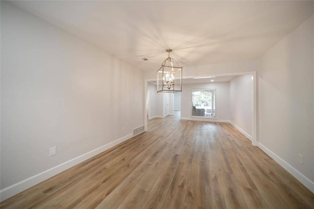 4333 Harvest Hill Road, Dallas, TX 75244 Open-concept interior featuring wood-finish flooring, neutral wall paint, and a decorative lantern-style metal pendant light