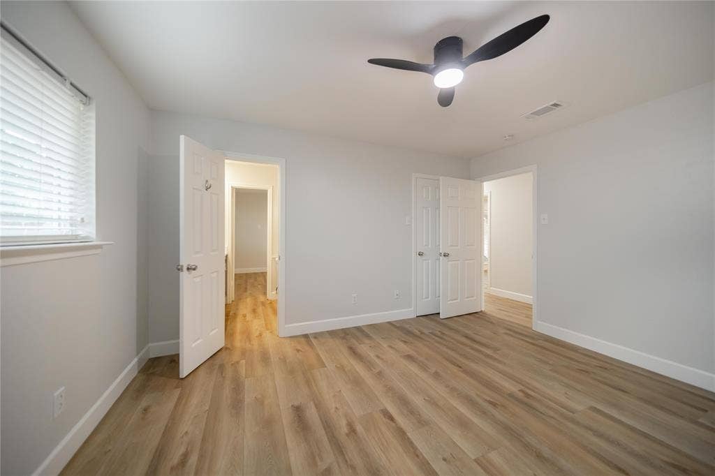 4333 Harvest Hill Road, Dallas, TX 75244 Neutral-toned interior featuring wood-finish flooring, a modern three-blade ceiling fan with integrated lighting, and horizontal slatted window blinds