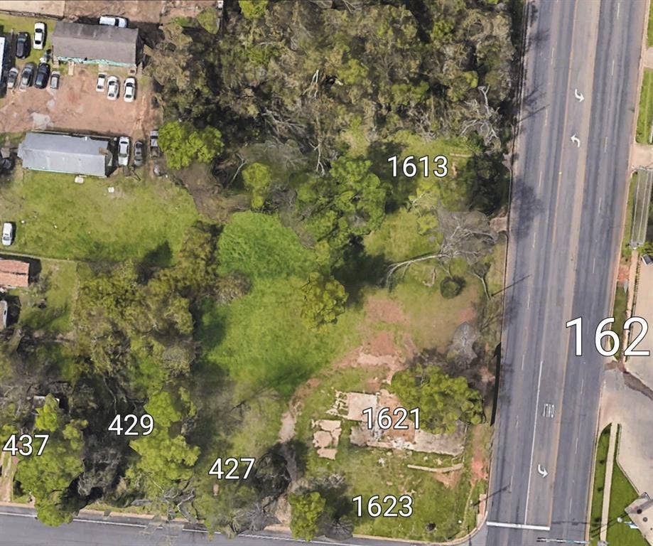 1621 E Front Street, Tyler, TX 75702 Expansive corner parcel featuring mature trees, established grass cover, and direct access to a paved thoroughfare