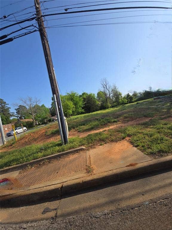 1621 E Front Street, Tyler, TX 75702 Vacant lot featuring a concrete curb, metal storm drain grate, and mature perimeter trees