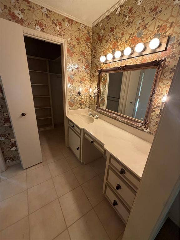 305 Westway Circle, Rockwall, TX 75087 Built-in vanity featuring a solid surface countertop, integrated sink, and ample cabinetry, paired with a framed wall mirror and multi-bulb vanity light, finished with large-format tile flooring and a walk-in storage area with built-in shelving