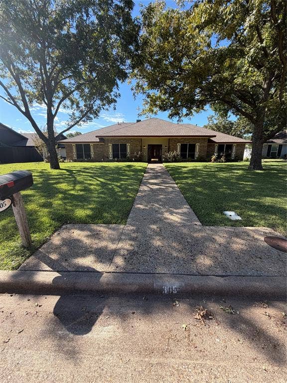 305 Westway Circle, Rockwall, TX 75087 Single-story brick exterior featuring a hip roof, concrete walkway, and mature trees