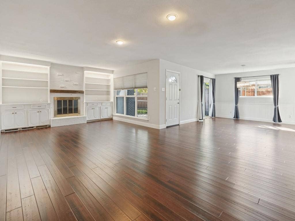 11321 Park Central Place, Dallas, TX 75230 Open-concept room featuring wood-finish flooring, a fireplace with a wood mantel, built-in shelving and cabinetry, recessed lighting, and wall-panel molding