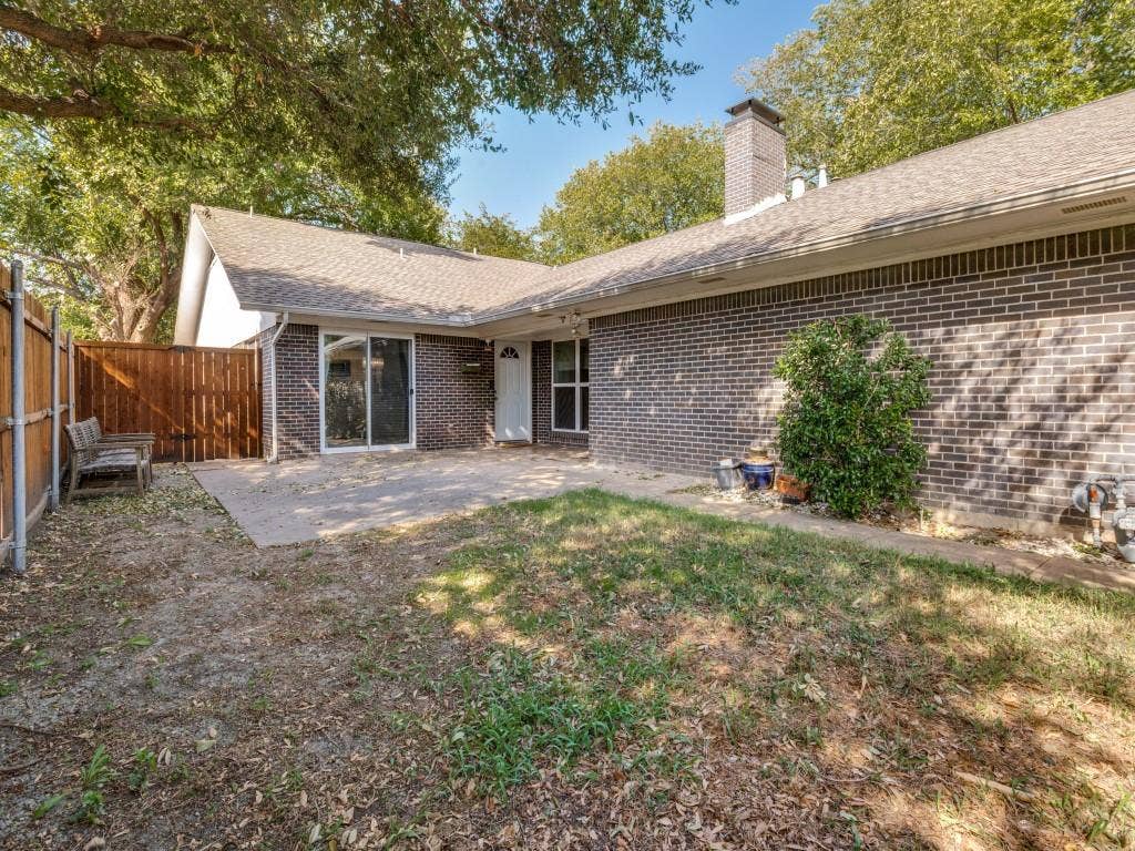11321 Park Central Place, Dallas, TX 75230 Brick exterior featuring a masonry chimney, concrete patio, and wood privacy fencing