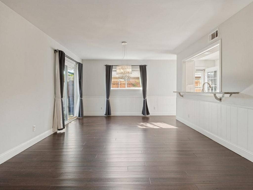 11321 Park Central Place, Dallas, TX 75230 Interior featuring dark wood-finish flooring, white wainscoting, a tiered crystal chandelier, and a pass-through opening with an extended stone ledge