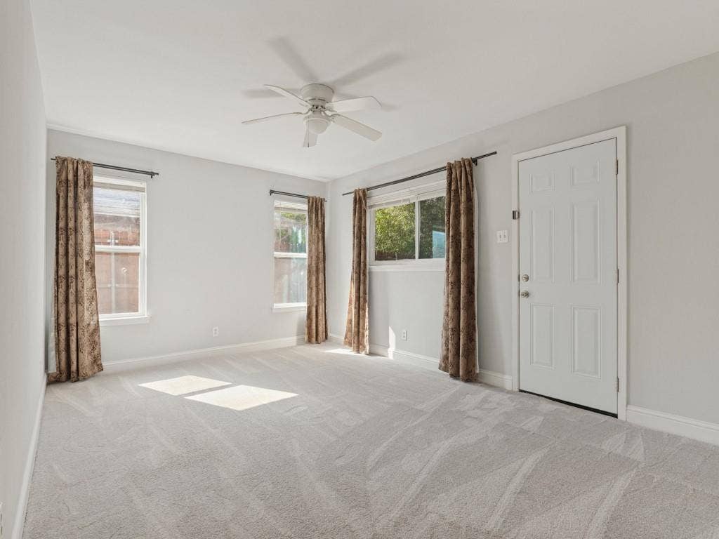 11321 Park Central Place, Dallas, TX 75230 Neutral-toned interior space featuring light-colored wall-to-wall carpeting, three windows with natural light exposure, and a ceiling-mounted fan