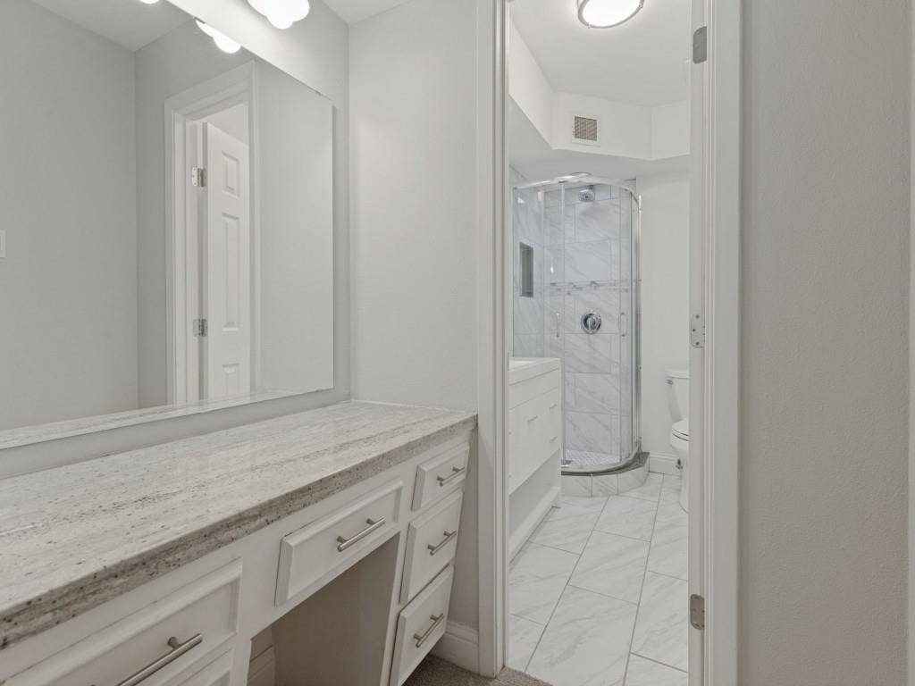 11321 Park Central Place, Dallas, TX 75230 White vanity with stone countertop, large wall-mounted mirror, corner shower enclosure with tiled surround, and tile flooring