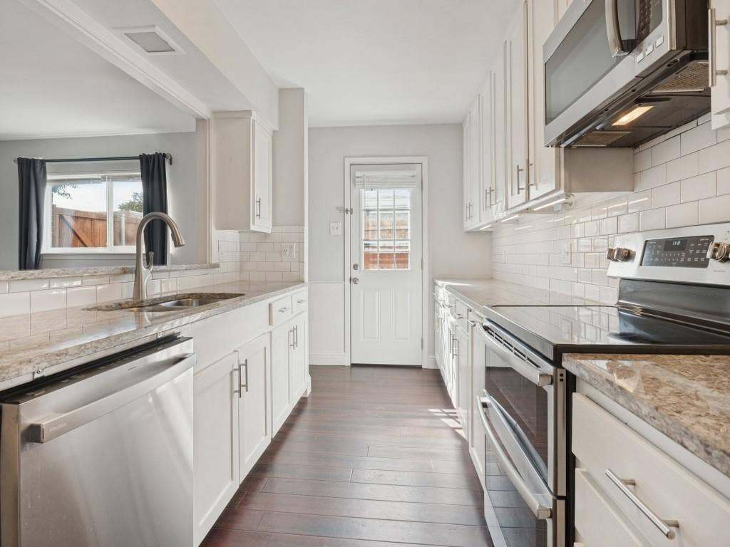 11321 Park Central Place, Dallas, TX 75230 Kitchen featuring white cabinetry, stone-finish countertops, subway tile backsplash, stainless steel appliances, and wood-finish flooring