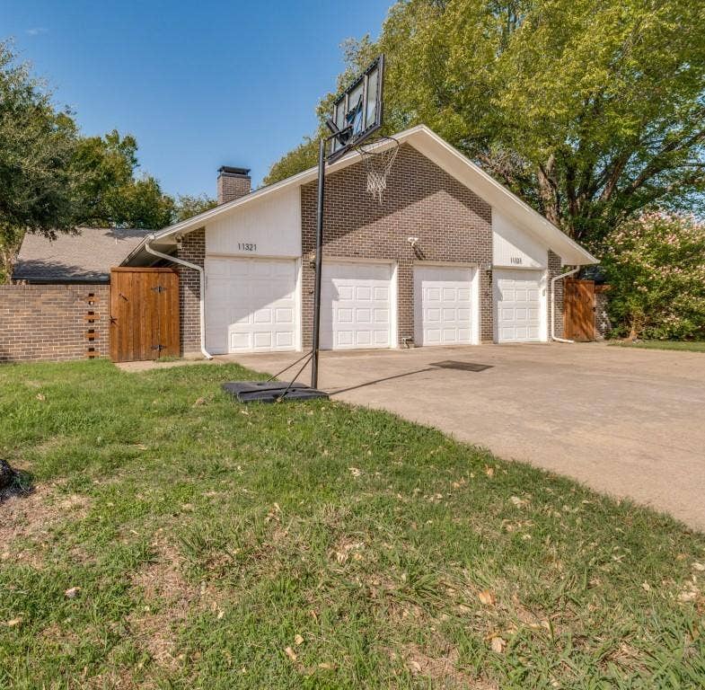 11321 Park Central Place, Dallas, TX 75230 Four-car garage with white paneled doors, brick exterior cladding, and wood-paneled privacy fencing
