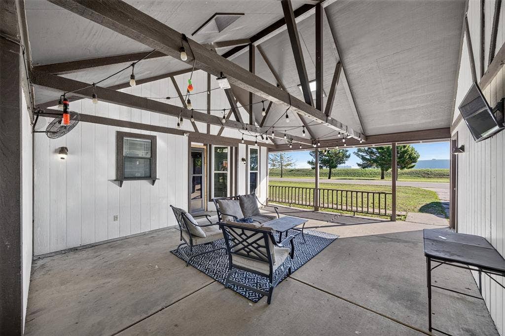 113 Dove Avenue, Red Oak, TX 75154 Covered patio featuring a vaulted ceiling with exposed timber trusses, concrete flooring, and an attached wood railing overlooking open grounds