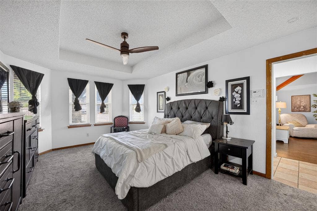 113 Dove Avenue, Red Oak, TX 75154 Tray ceiling featuring a central multi-blade ceiling fan, expansive triple-pane bay windows, and neutral carpeting