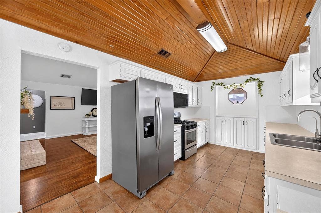 113 Dove Avenue, Red Oak, TX 75154 Kitchen featuring vaulted wood-plank ceilings, tile flooring, white cabinetry, a built-in recessed display niche, and stainless steel appliances