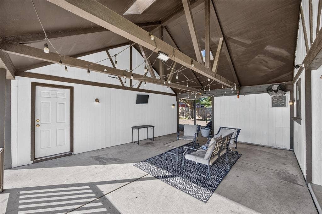 113 Dove Avenue, Red Oak, TX 75154 Covered patio featuring an exposed-beam vaulted ceiling, concrete flooring, exterior-grade wall paneling, and string lighting