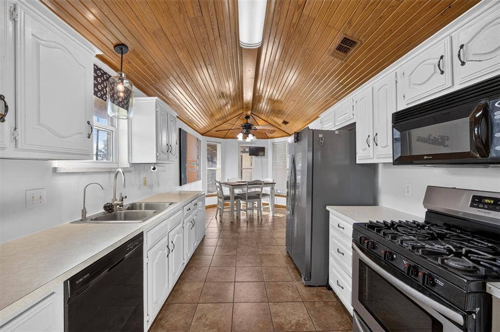 113 Dove Avenue, Red Oak, TX 75154 Kitchen featuring vaulted wood-plank ceilings, white cabinetry, tile flooring, stainless steel appliances, and a double-basin stainless steel sink