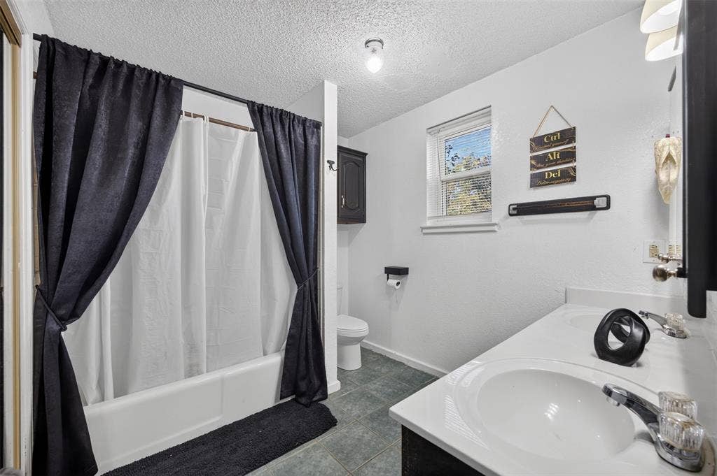 113 Dove Avenue, Red Oak, TX 75154 Dual-sink vanity with integrated countertop, tiled flooring, bathtub and shower combination, wall-mounted cabinetry, and window