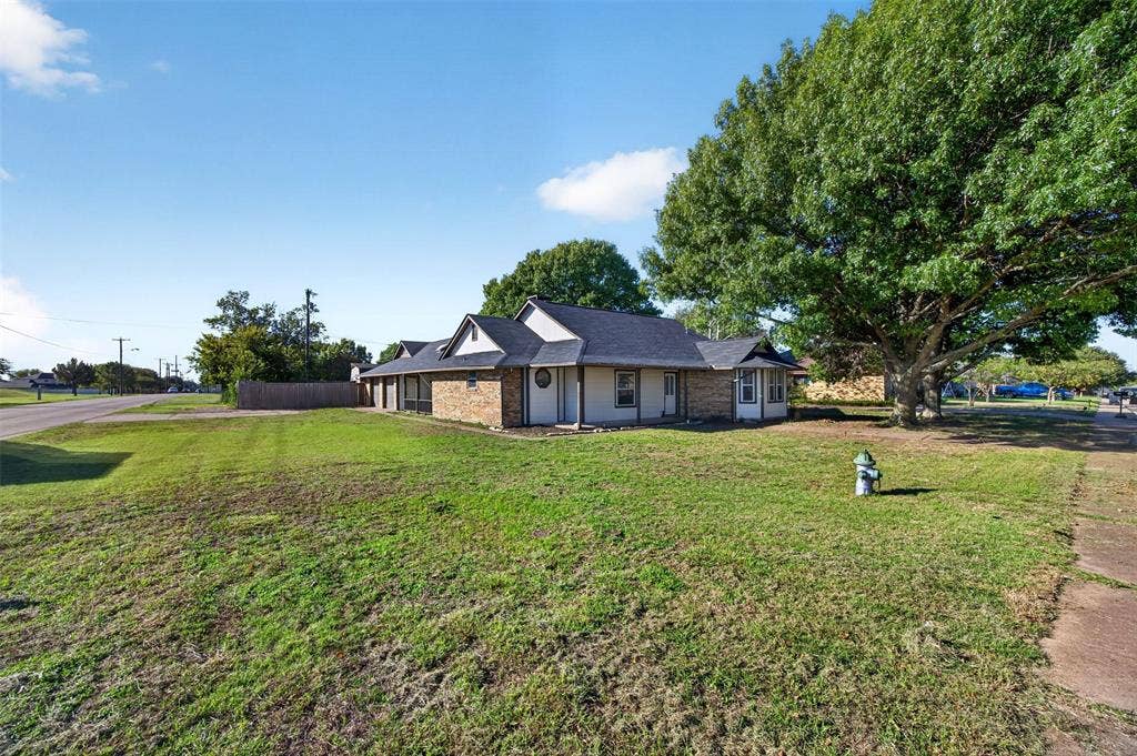 113 Dove Avenue, Red Oak, TX 75154 Single-story brick and siding exterior featuring an asphalt shingle roof, bay window, and expansive lawn with mature shade trees