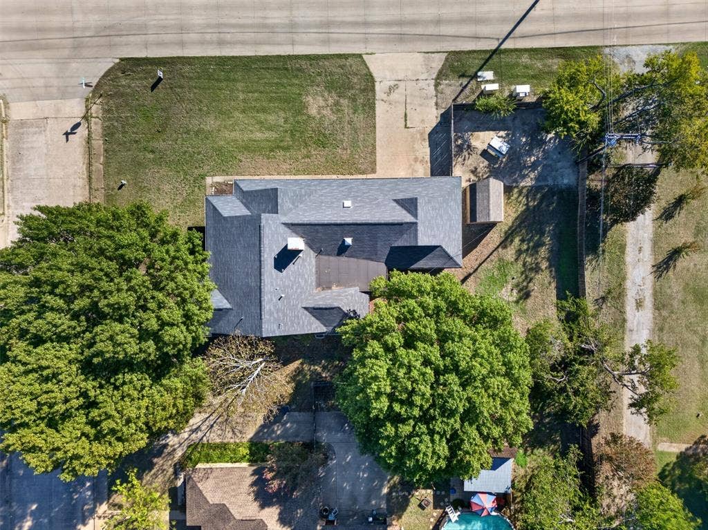 113 Dove Avenue, Red Oak, TX 75154 Aerial perspective featuring a multi-gabled asphalt shingle roof, mature canopy trees, concrete driveway, and a detached storage structure on a rectangular lot