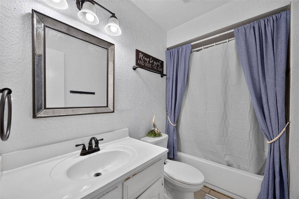 113 Dove Avenue, Red Oak, TX 75154 Bathroom featuring a white vanity with an integrated basin, matte black faucet, framed mirror, three-light vanity fixture, and a bathtub-shower combination