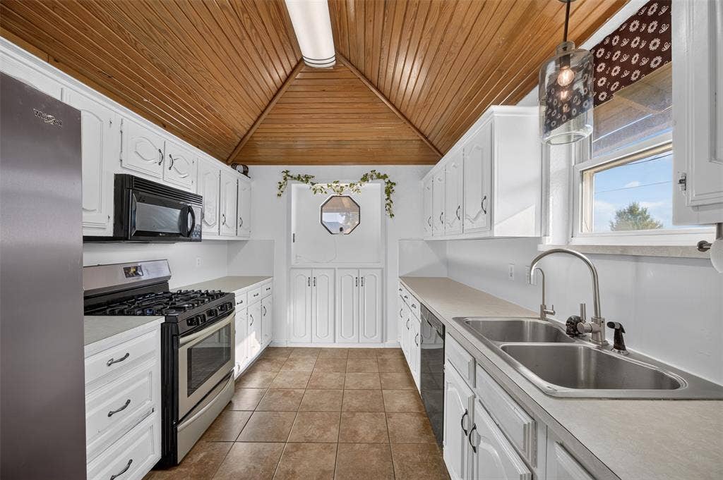 113 Dove Avenue, Red Oak, TX 75154 Kitchen featuring white cabinetry, vaulted wood-paneled ceiling, stainless steel gas range, tiled flooring, and dual-basin stainless steel sink with high-arch faucet