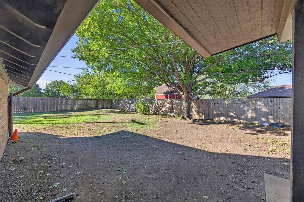 113 Dove Avenue, Red Oak, TX 75154 Covered patio area opening to a spacious backyard featuring a wood privacy fence and a mature tree
