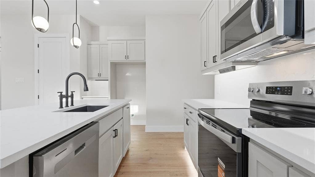 2816 Marburg Street, Dallas, TX 75215 Kitchen featuring shaker-style cabinetry, white countertops, stainless steel appliances, wood-finish flooring, and matte black hardware