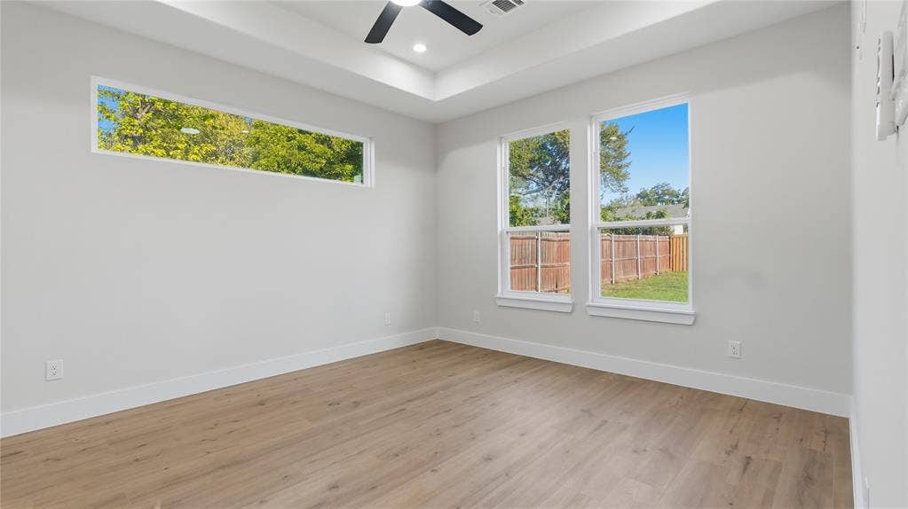 2816 Marburg Street, Dallas, TX 75215 Tray ceiling featuring a central matte black ceiling fan, wood-finish flooring, and expansive windows providing natural light